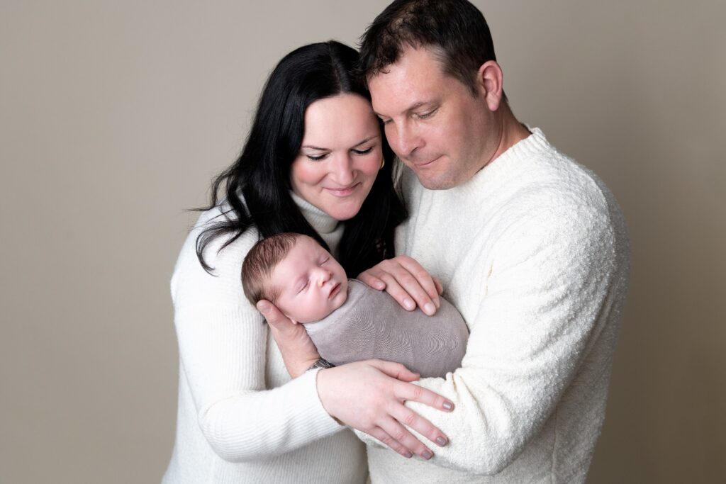 Parents holding their newborn during a family photography session, styled in neutral tones by a Philadelphia family photographer