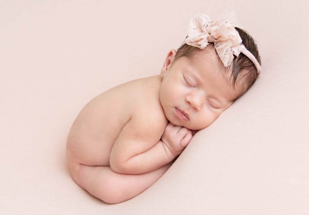 Sleeping newborn baby girl posed on a soft pink blanket during a Main Line newborn photography session