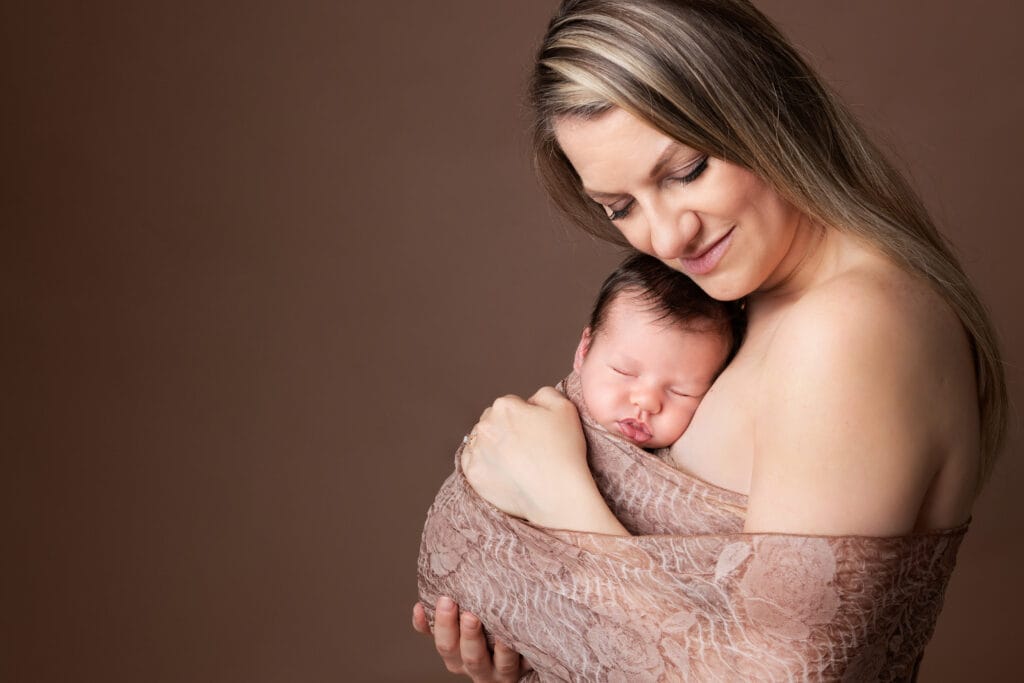 Mother holding her sleeping newborn baby during a studio photography session