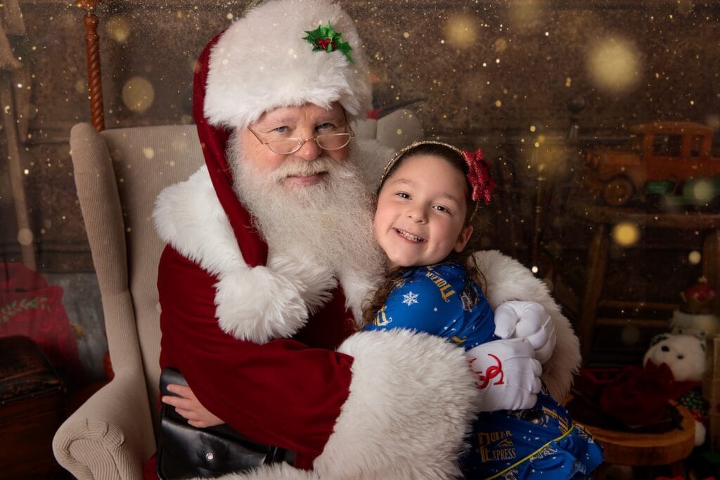 Child smiling while hugging Santa during a Christmas portrait session