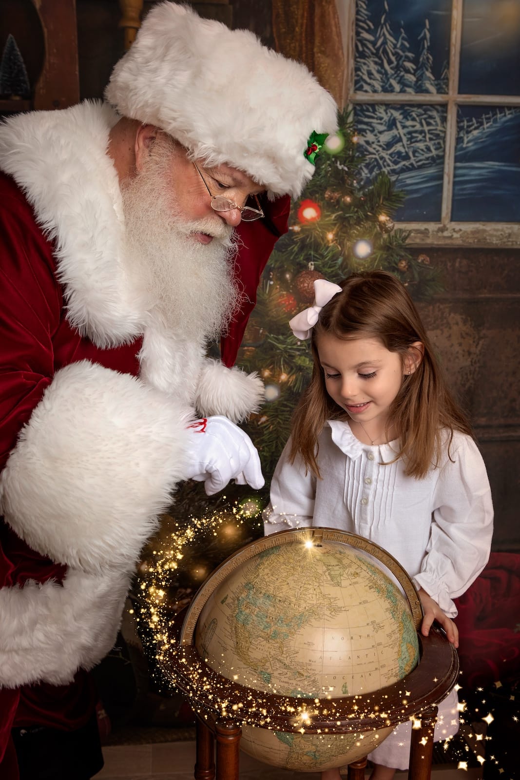 Santa and a young girl looking at a globe during a magical Christmas portrait session.