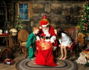 Two children look into Santa’s glowing Christmas bag during an interactive Santa portrait session.