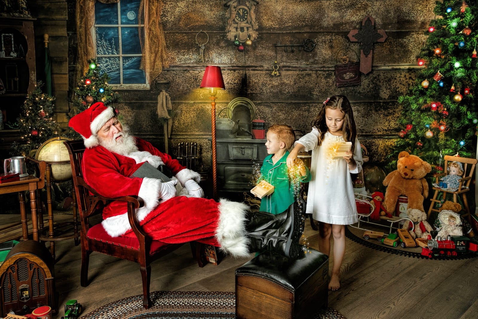 Two children play with magical Christmas boxes while Santa pretends to sleep in his chair.