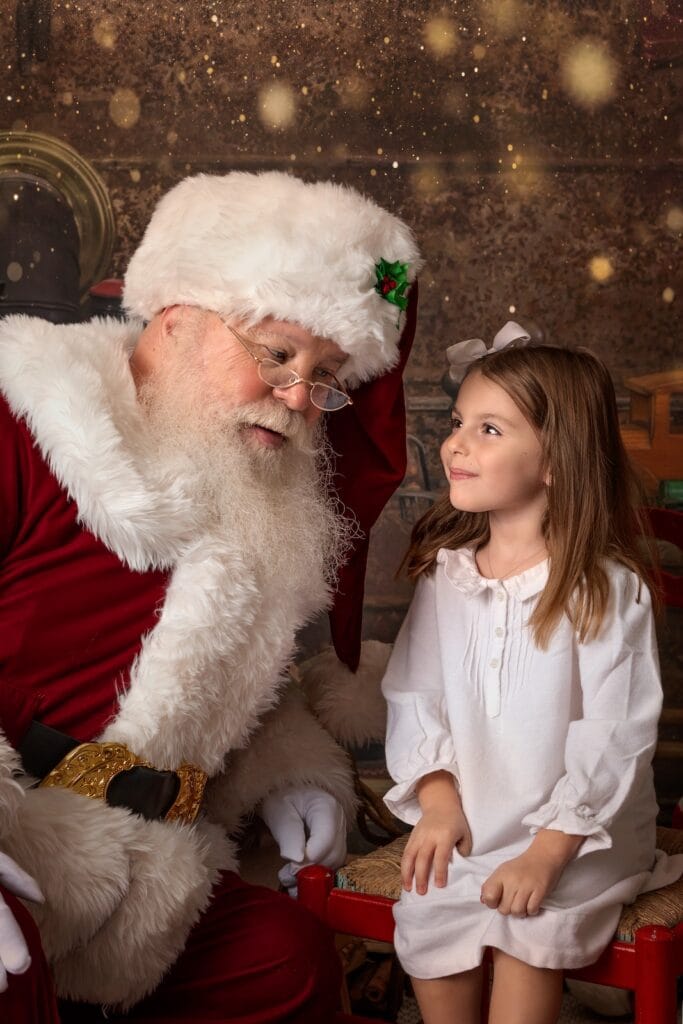 Young girl talking with Santa during a magical Christmas portrait session.