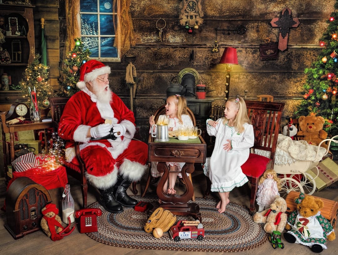 Santa talks with two children over cookies and milk during a Christmas photography experience near Wayne, PA.