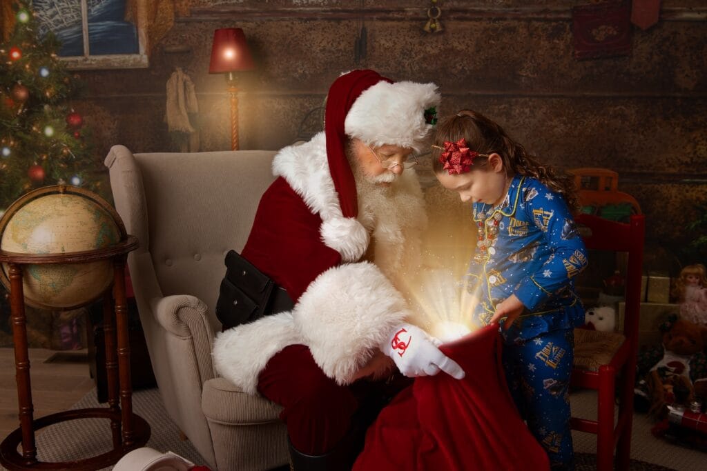 Santa presenting a special Christmas gift to a child during a Santa photography session