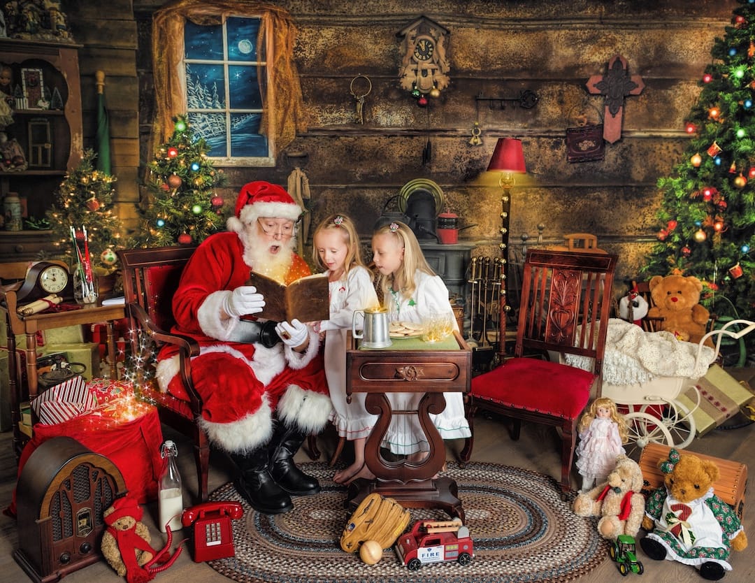 Santa reads a glowing magical book with two children during a Santa photography experience near Bryn Mawr, PA.