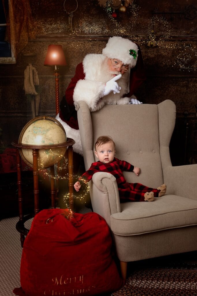 Santa playfully surprising a baby during an interactive Christmas portrait experience.